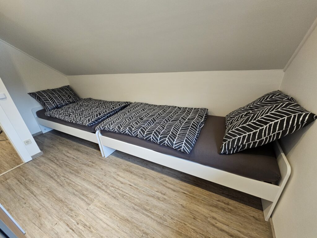 Zwei hintereinander angeordnete Einzelbetten unter der Dachschräge